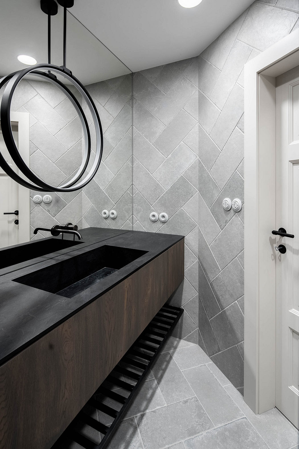 Modern bathroom with herringbone tiles, black fixtures, and wooden vanity.