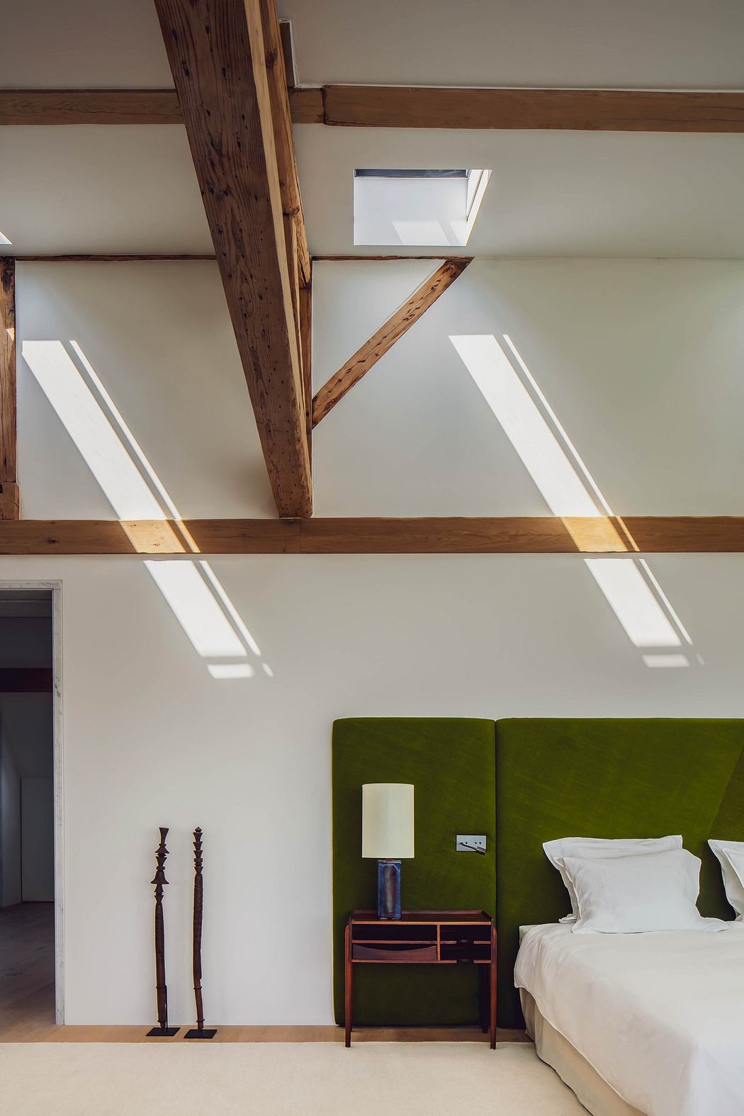 Modern attic bedroom with exposed beams and skylights.