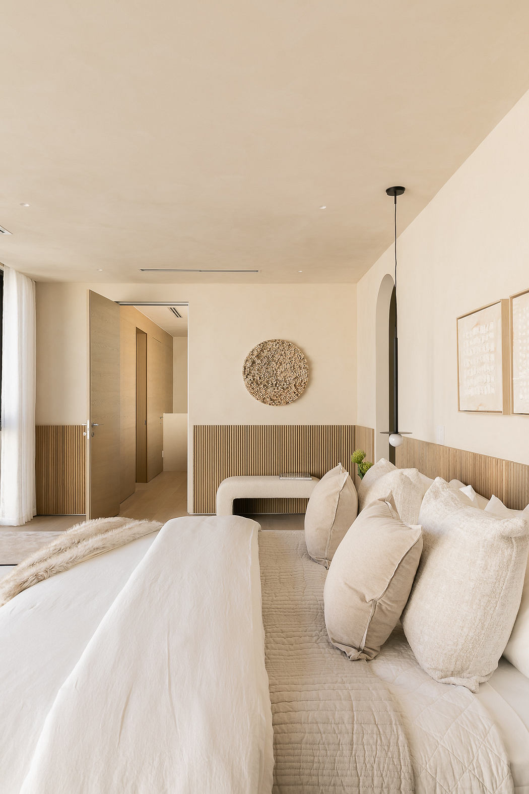 Neutral-toned bedroom with plush bedding and minimalist decor.