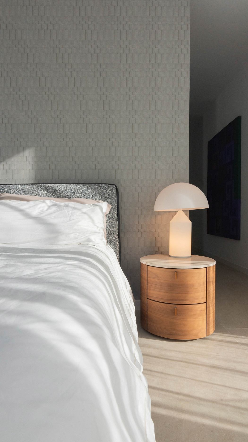 Minimalist bedroom with a stylish lamp on a wooden bedside table.