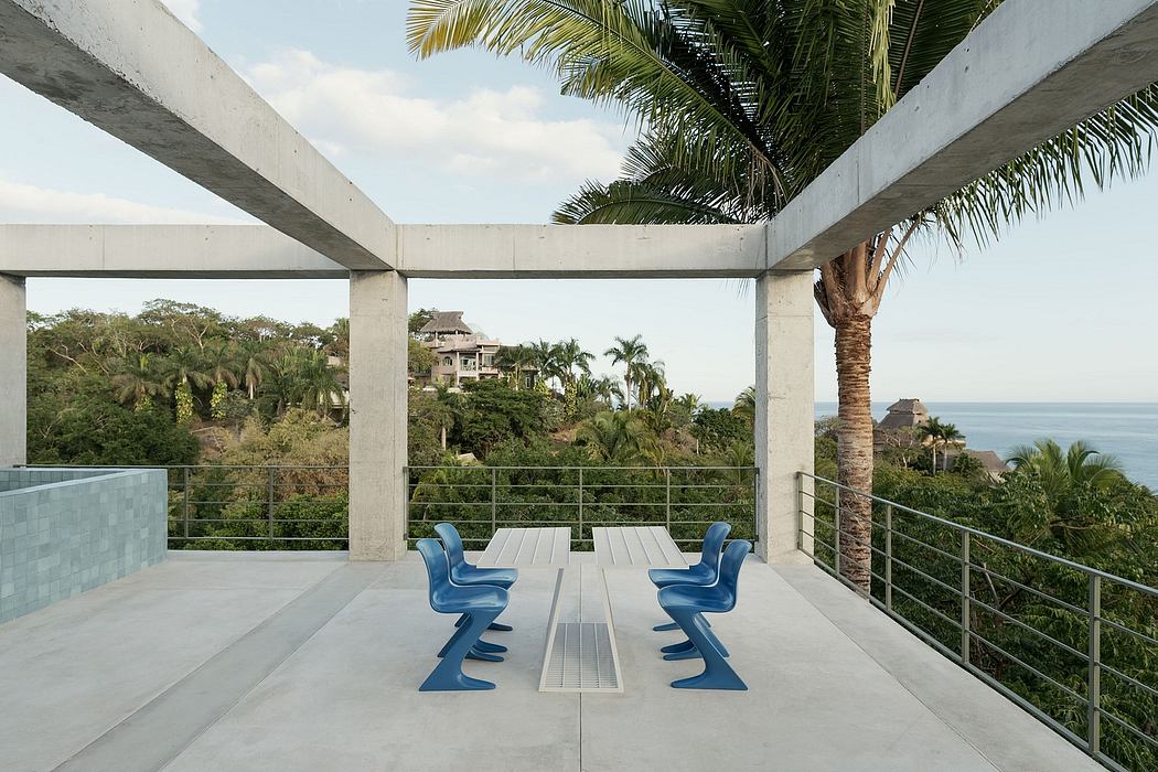 Modern outdoor terrace with blue chairs, overlooking the sea.