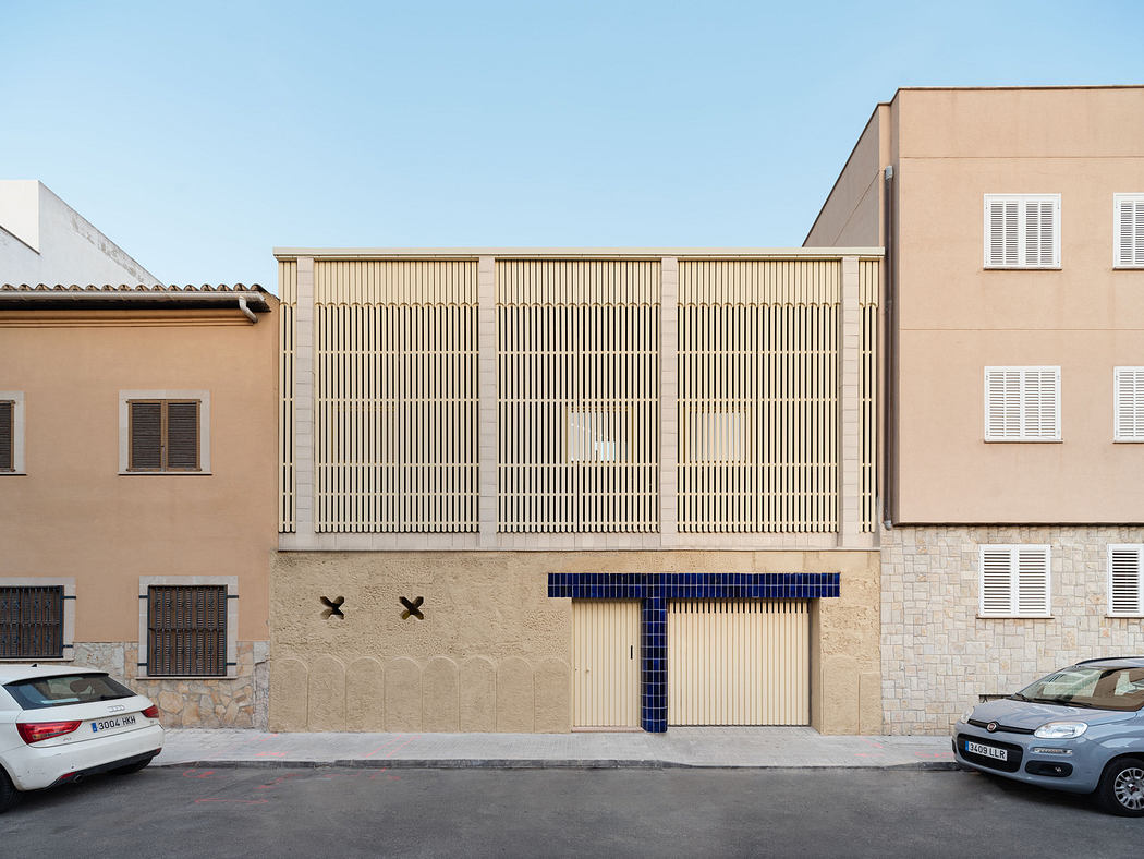 Modern beige building facade with symmetrical louvered design and blue accents.