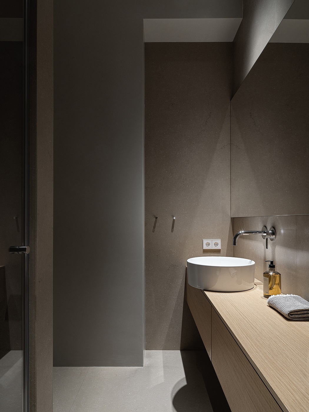 Minimalist bathroom with a sleek basin on a wooden vanity, muted tones, and