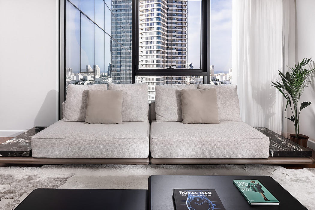 Modern living room with a beige sofa, coffee table, and city view through large