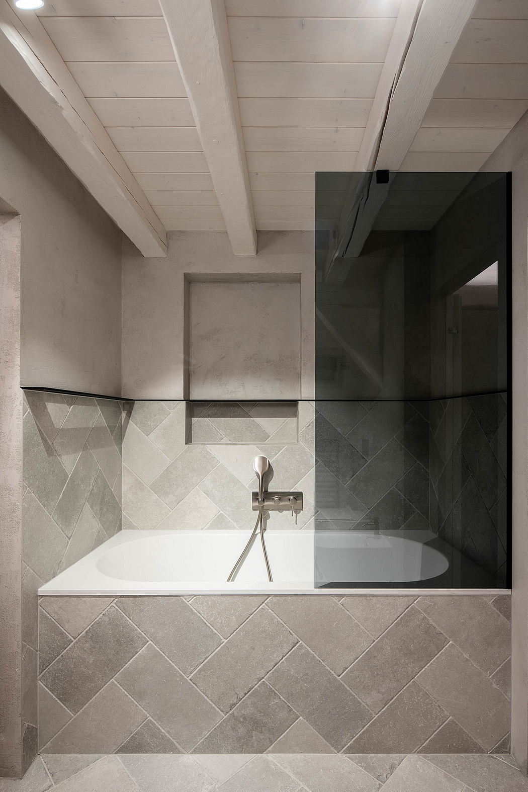 Modern bathroom with a built-in tub, herringbone tiles, and wooden ceiling