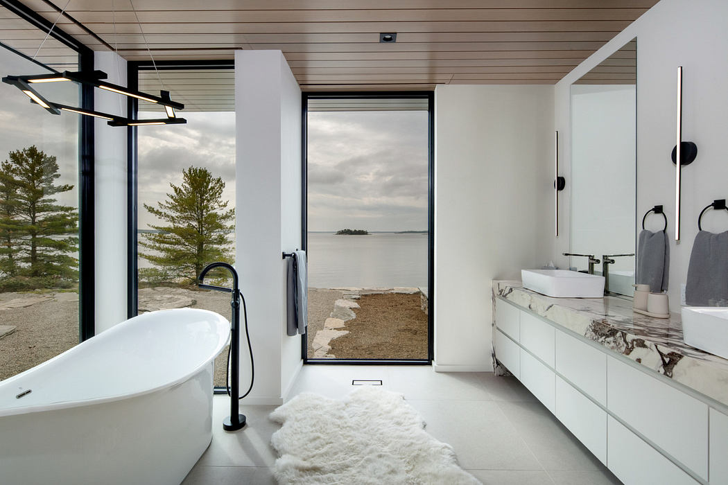 Modern bathroom with a freestanding tub and lake view.