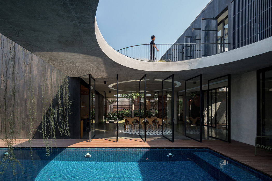 Modern courtyard with pool, curved walkway overhead, and glass walls.