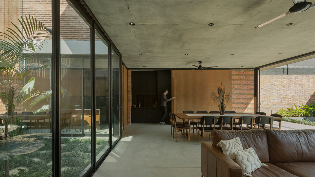 Contemporary living space with exposed concrete ceiling and glass walls overlooking a garden.