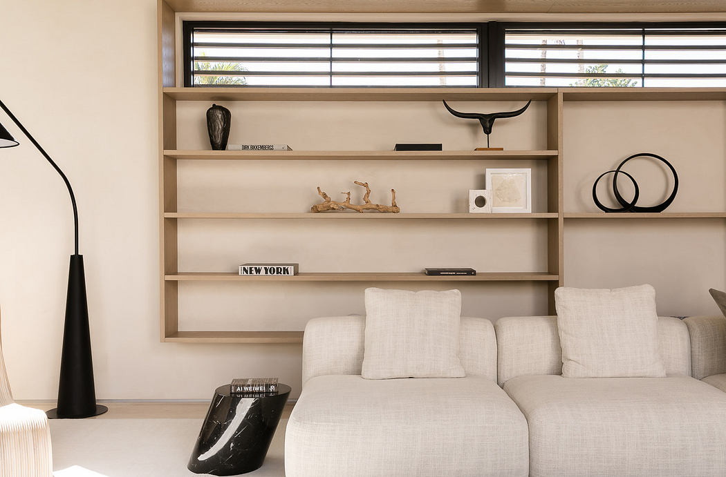 Modern living room with beige sofa, wooden shelves, and minimalist decor.