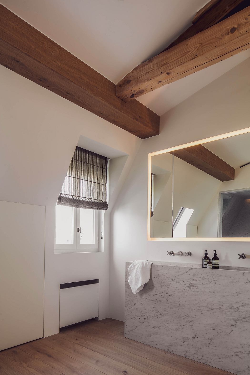 Minimalist bathroom with exposed wooden beams and marble sink.