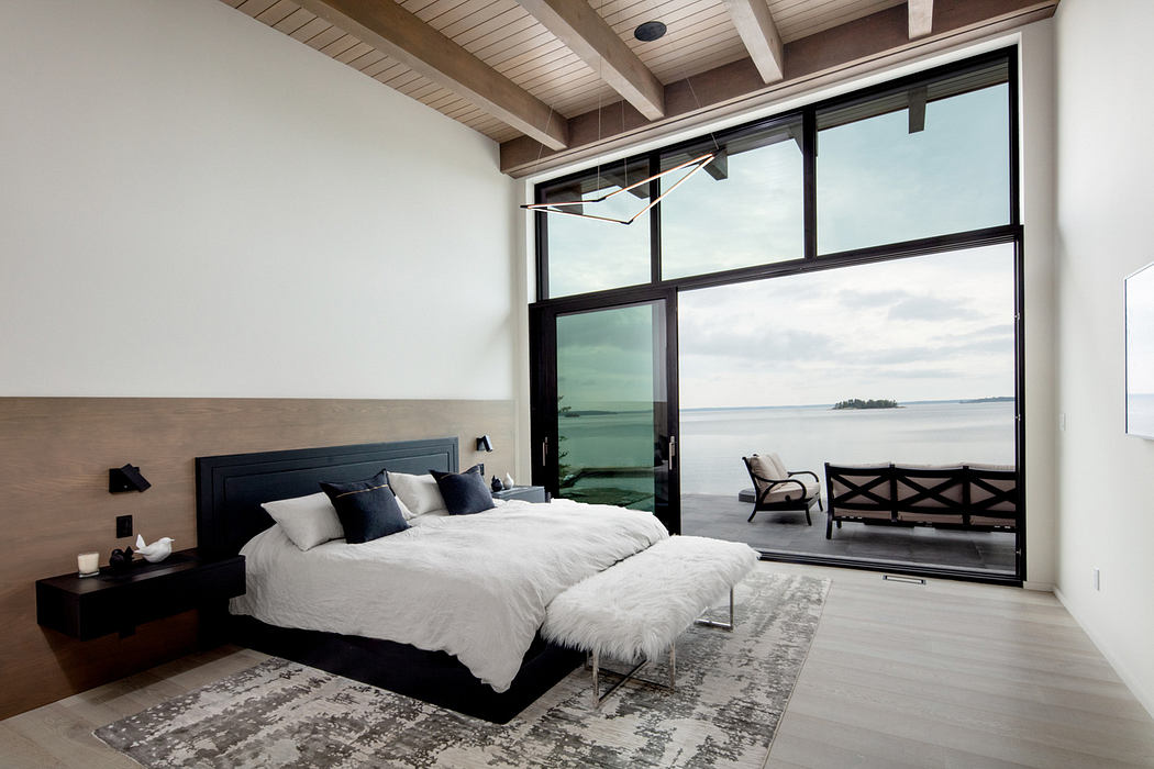 Contemporary bedroom with large windows overlooking a serene lake.