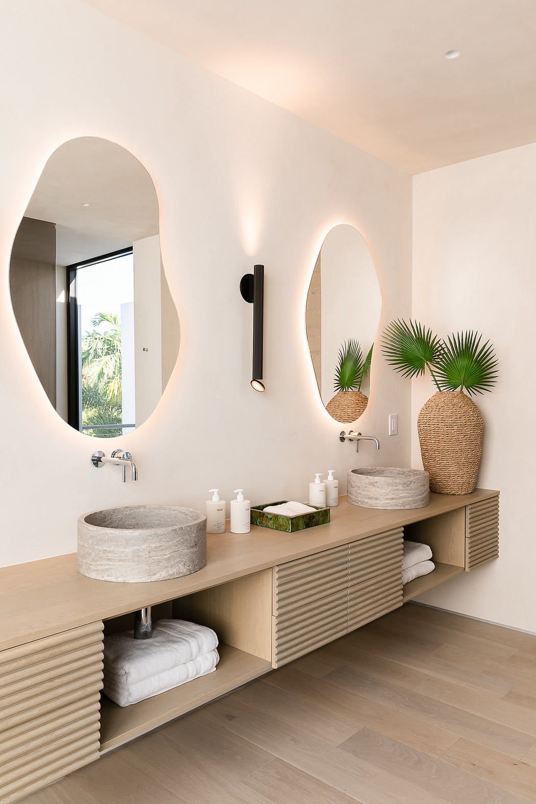 Modern bathroom with twin vessel sinks, oval mirrors, and wooden vanity.