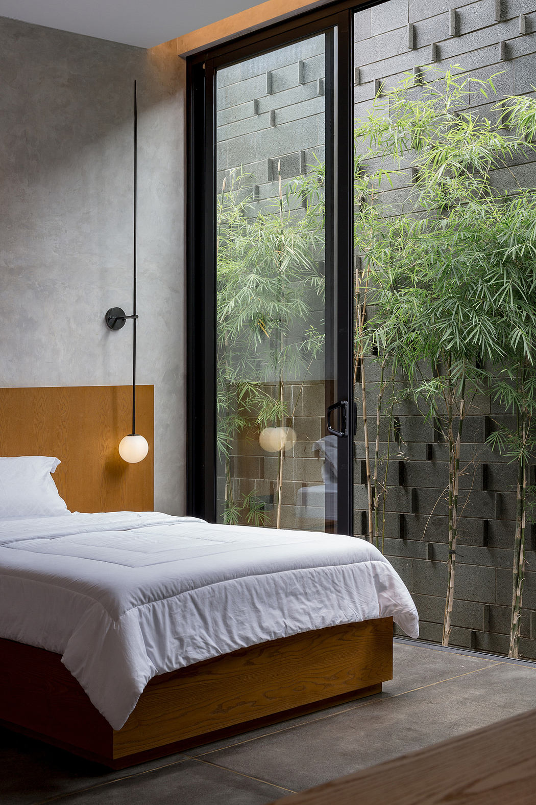 Modern bedroom with sleek wooden bed, large window, and view of bamboo outdoors.