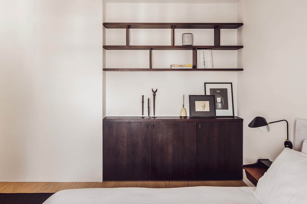Modern bedroom with a sleek wooden sideboard and floating shelves above.