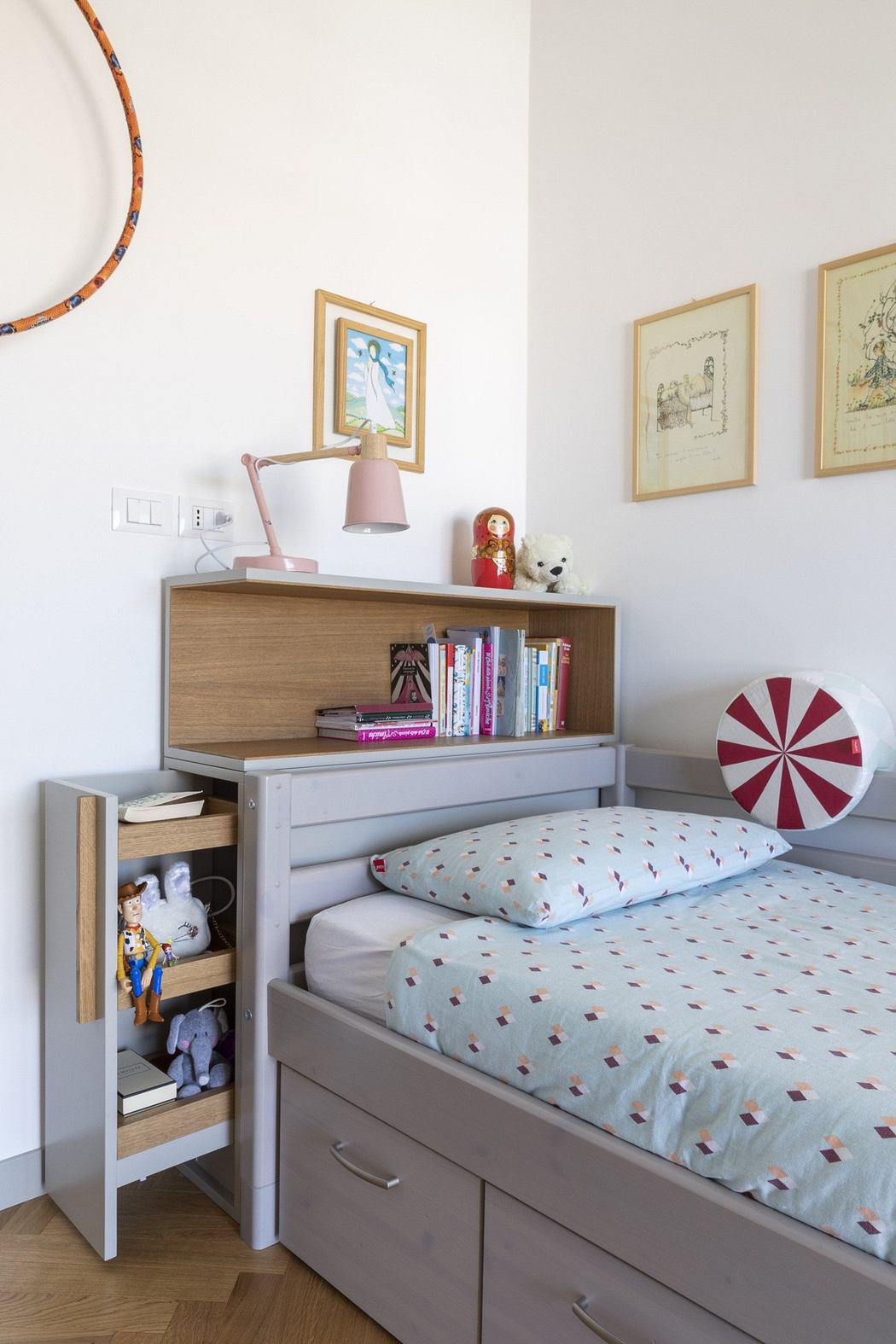A neatly organized child's bedroom with a single bed, bookshelf, and wall