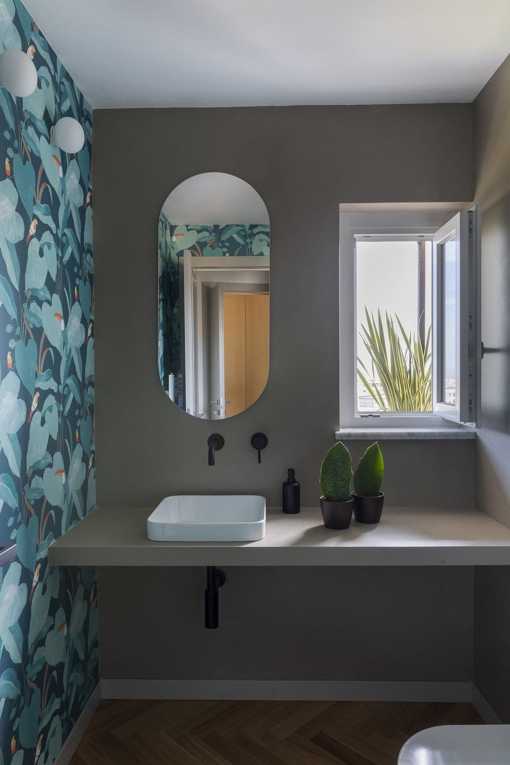 Chic bathroom with floral wallpaper, oval mirror, and floating sink.