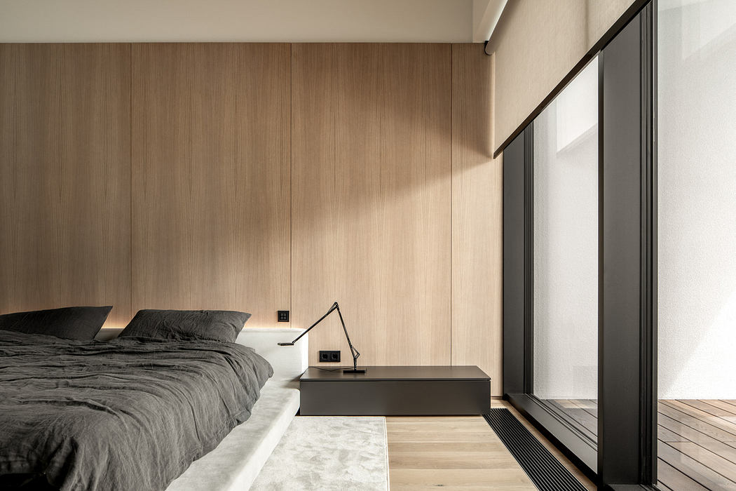 Minimalist bedroom with wood paneling and large window.