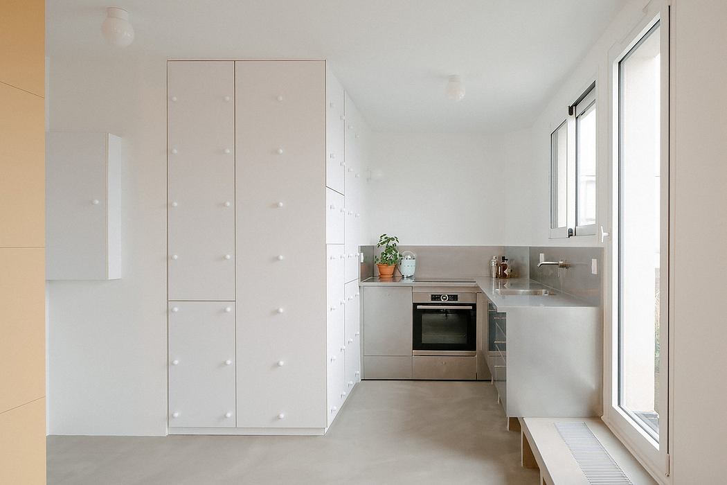 Modern minimal kitchen with white cabinets and stainless steel appliances.