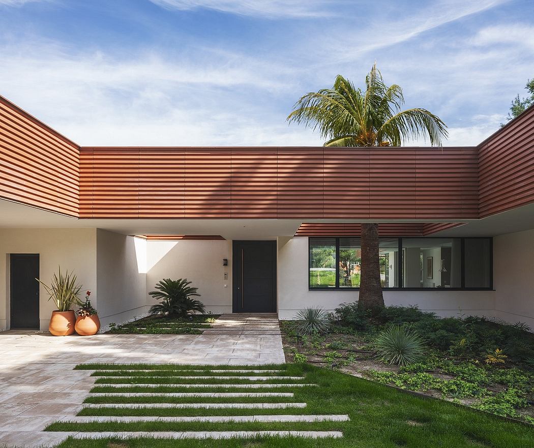 A modern home with a wooden facade, palm trees, and a well-landscaped entryway.