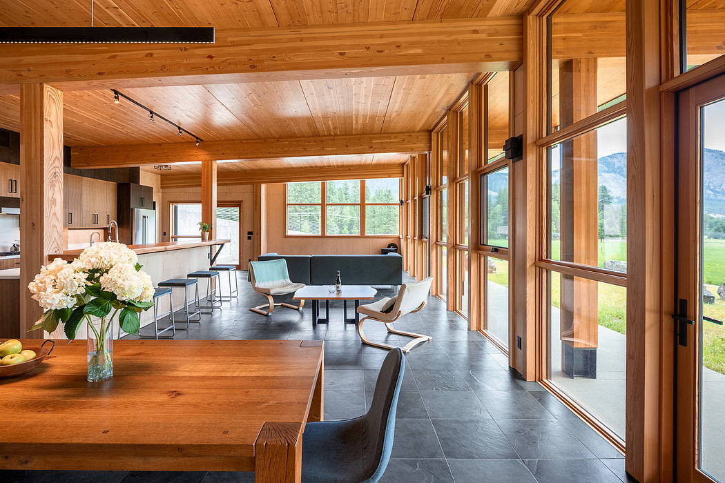 Rustic cabin interior with wooden beamed ceiling, large windows, and modern furnishings.