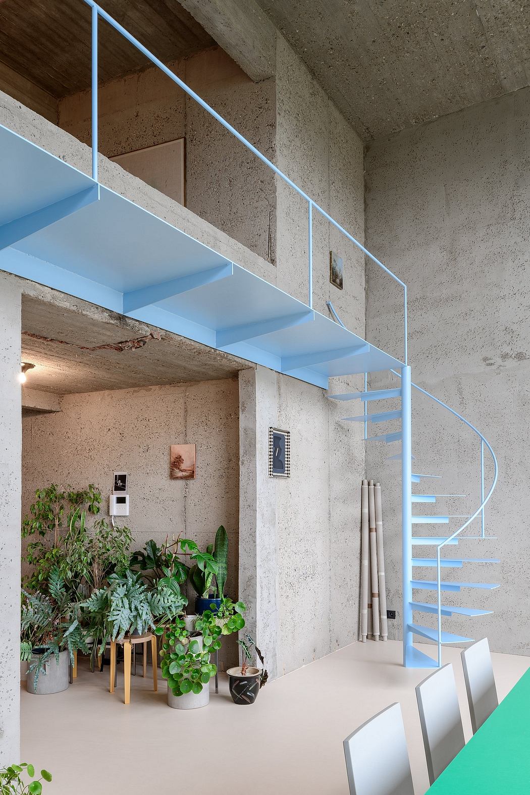 Modern interior with blue staircase, concrete walls, and indoor plants.