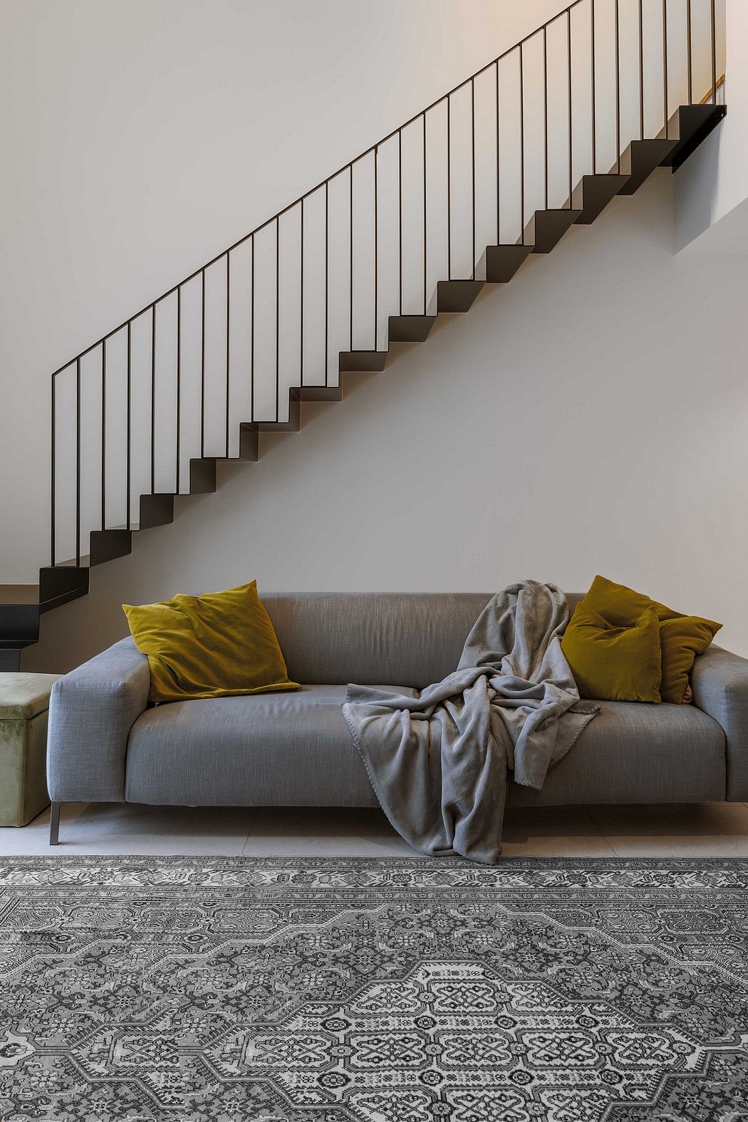 Modern living room with a grey sofa, decorative pillows, and a patterned rug