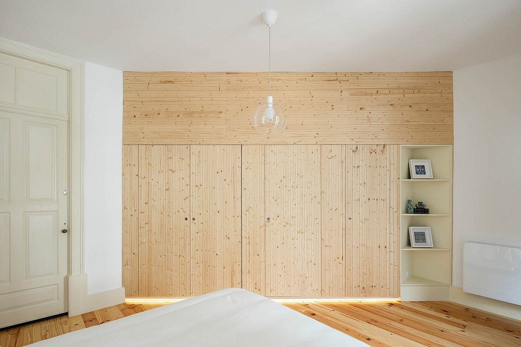 Minimalist bedroom with a wooden feature wall and herringbone floor.