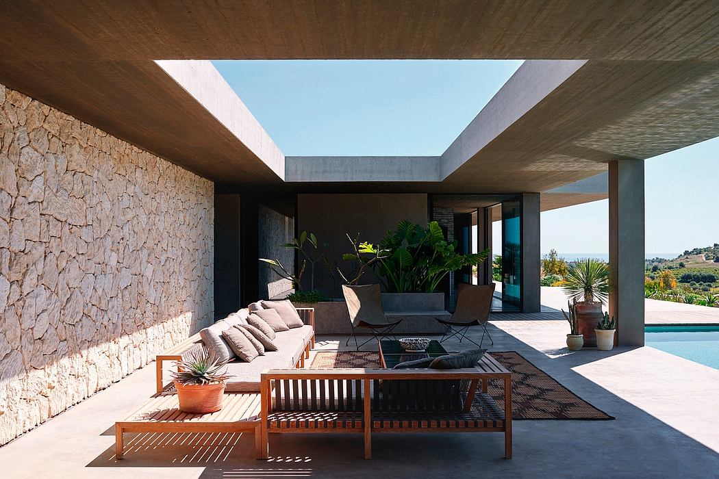 Modern terrace with stone wall, wooden furniture, and open view.