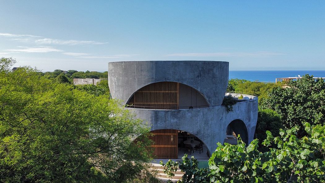 A modernist concrete structure with arched openings and a lush, verdant setting.