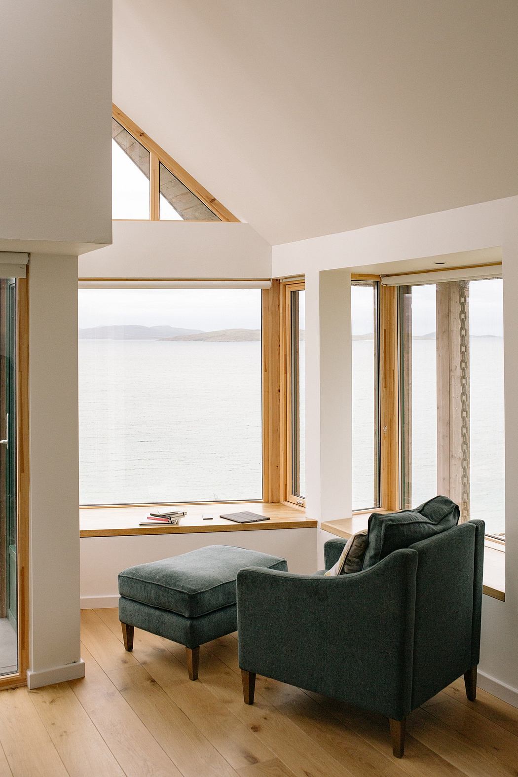 Cozy nook with armchair, ottoman, and sea view through large
