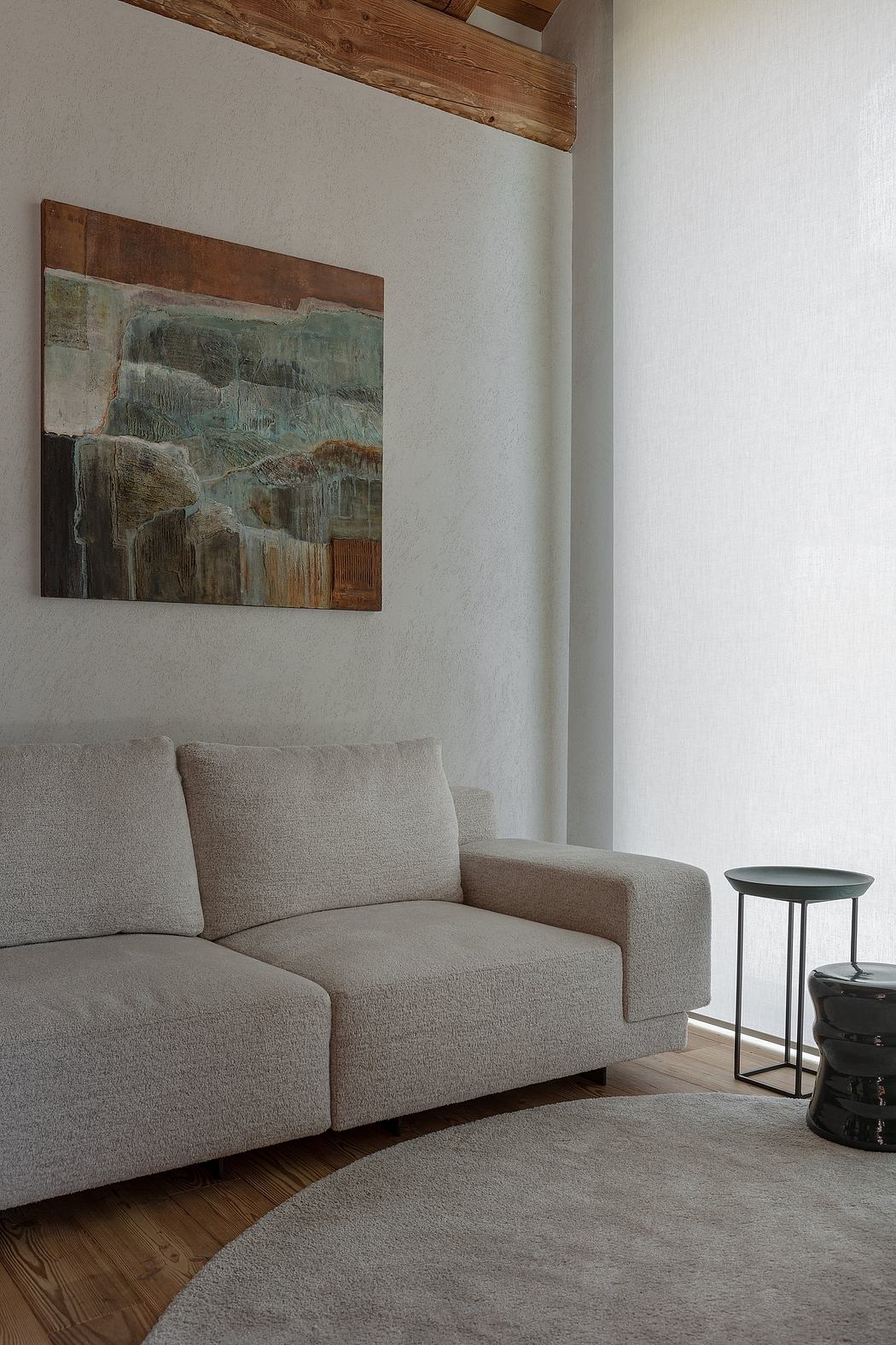 Minimalist living room corner with a beige sofa, round rug, and abstract wall
