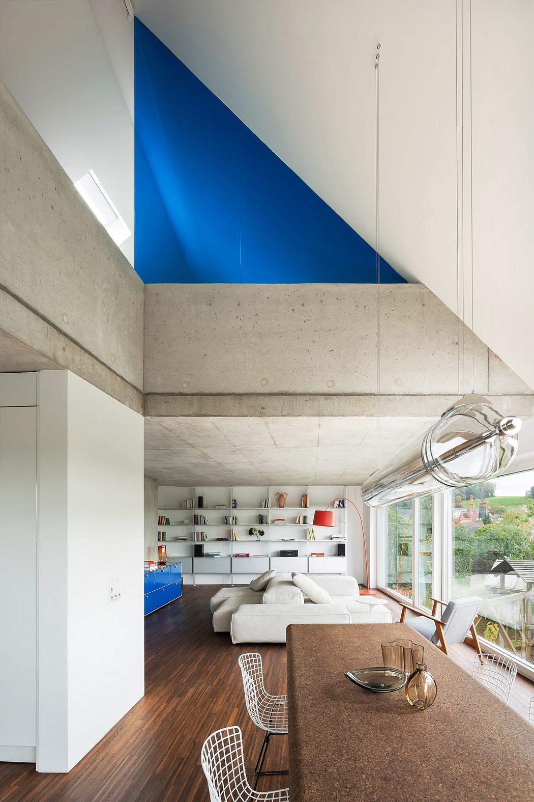 Striking architectural features: bold blue wall, open concrete ceiling, modern furniture.