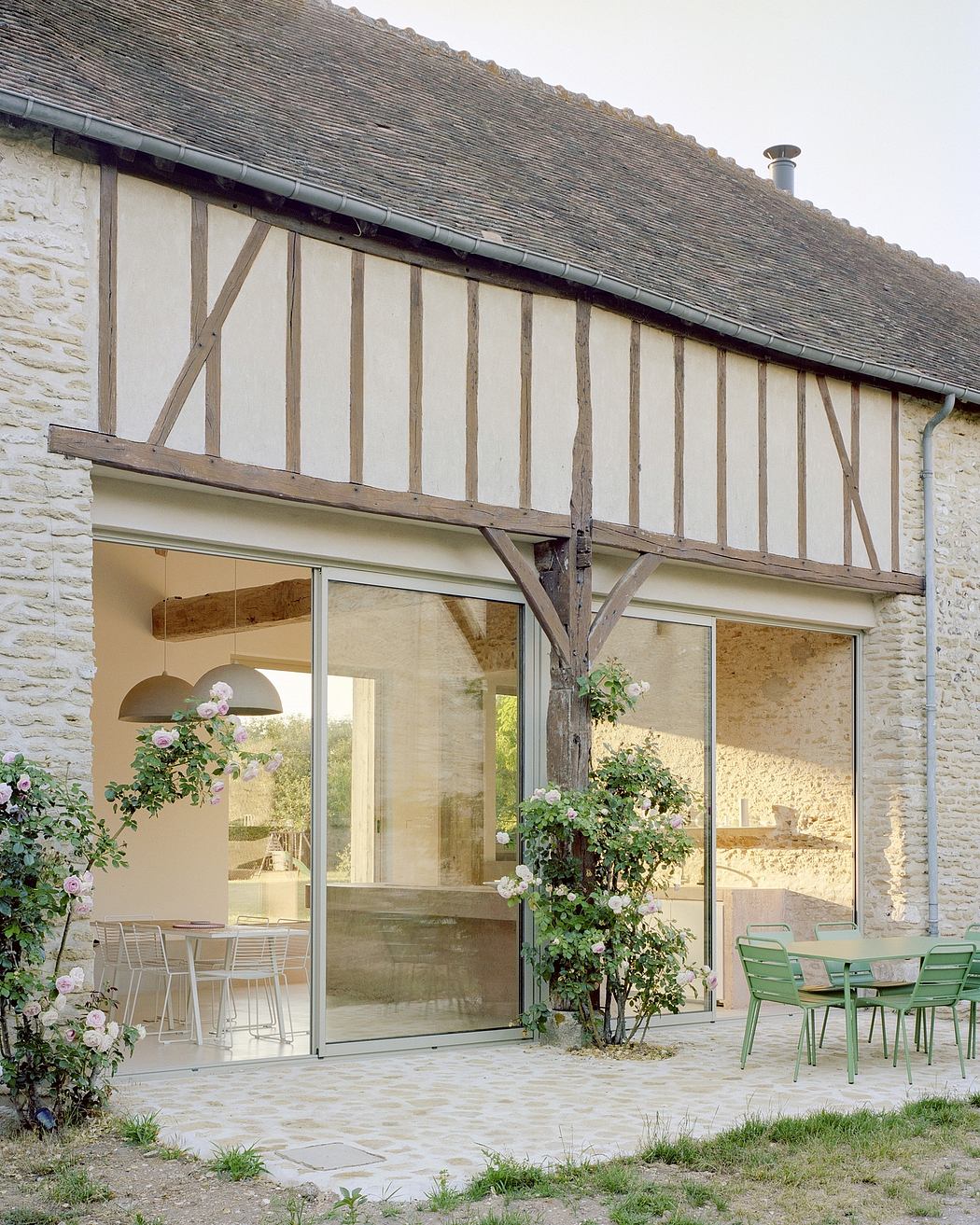 Contemporary half-timbered house with large glass doors and outdoor seating.