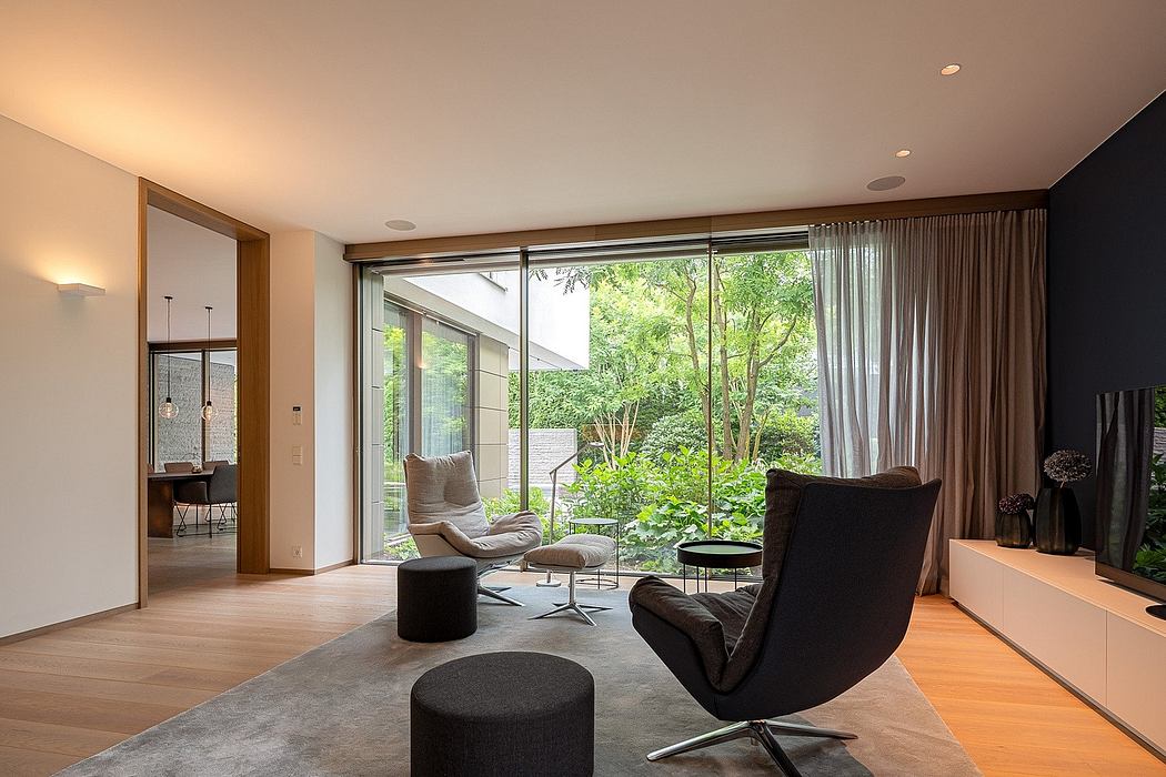 Spacious modern living room with large windows overlooking lush greenery and nature.