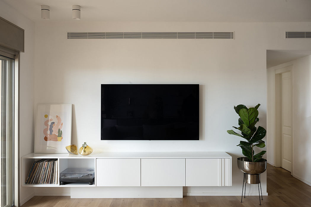 Modern living room with a wall-mounted TV and white storage cabinet.