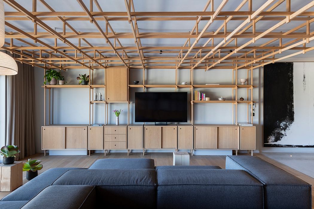 Minimalist living room with wooden truss ceiling, storage units, and a large TV.
