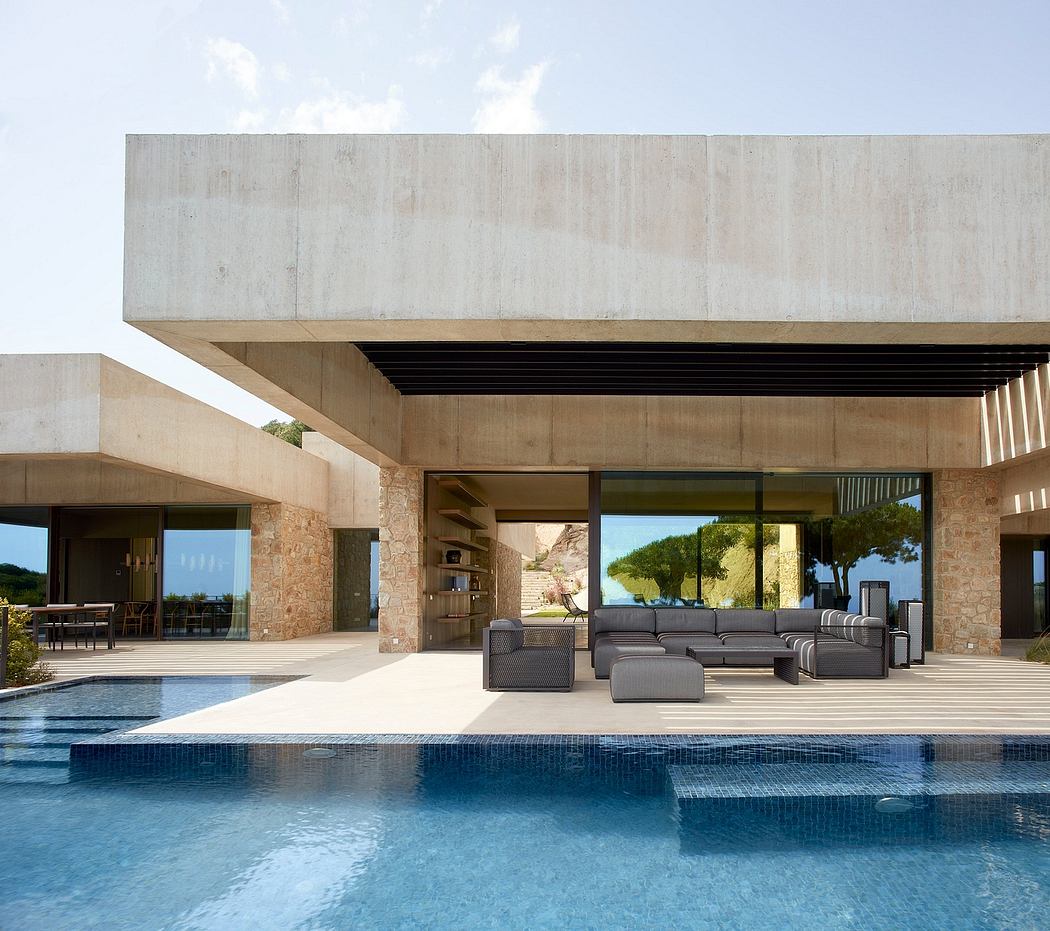 Contemporary villa with large glass doors, concrete overhangs, and poolside