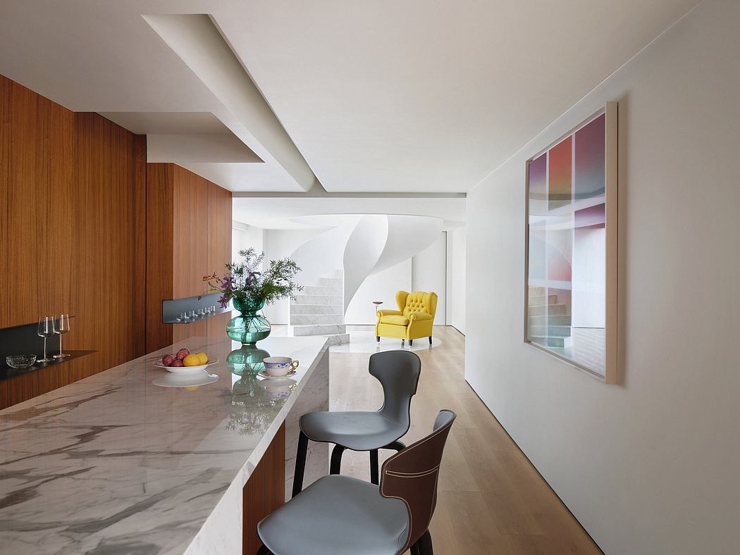 Modern open-concept kitchen with sleek marble countertops, wooden cabinetry, and minimalist furnishings.