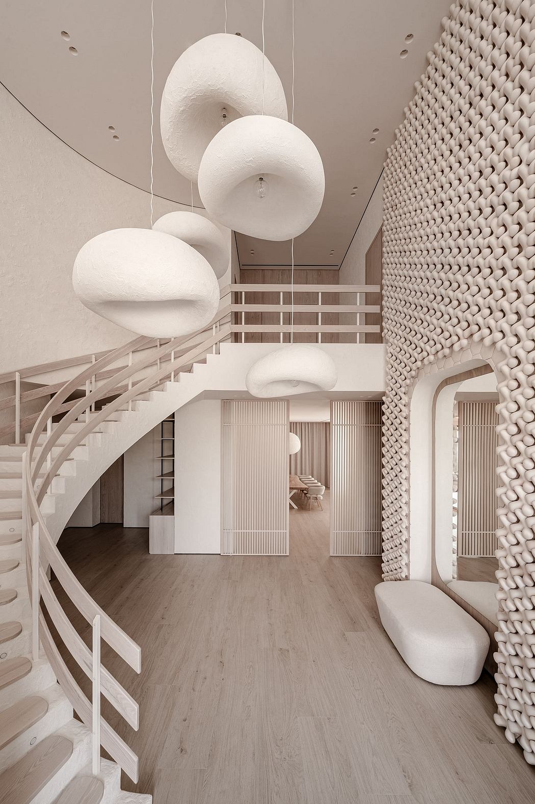 An architectural space with sculptural lighting fixtures, curved stairs, and intricate wall textures.