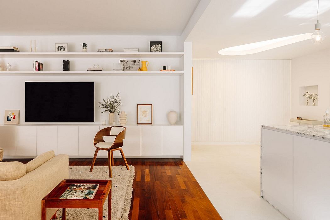 A modern, minimalist living room with built-in shelving, wood floors, and a cozy armchair.