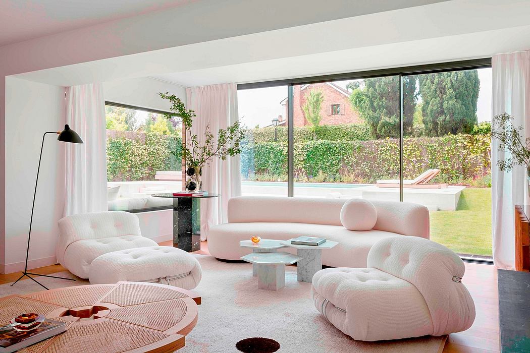 Elegant living room features large windows, plush white furniture, and sculptural accents.