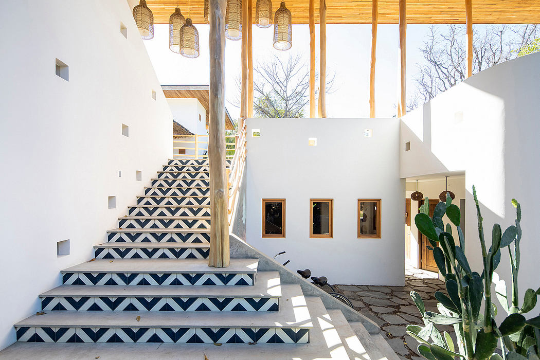 Contemporary courtyard with patterned staircase, wooden beams, and cactus plant.