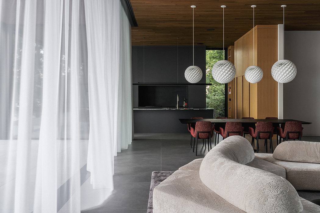 Elegant modern interior with sleek furnishings, pendant lights, and a view of nature.