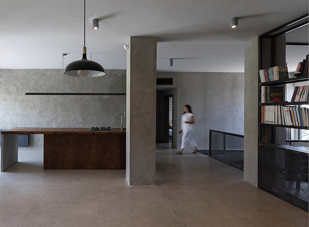 Minimalist interior with concrete walls, modern furniture, and a person walking through.