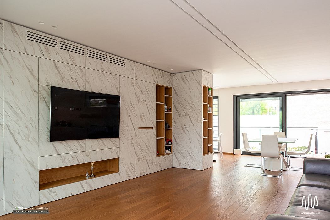 Elegant living room with marble wall panels, built-in shelves, and wood flooring. Stylish furnishings.