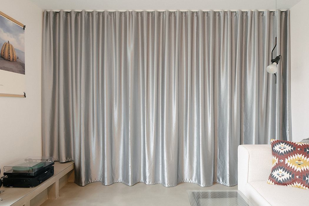 Modern living room with gray curtains, white sofa, and wall art.