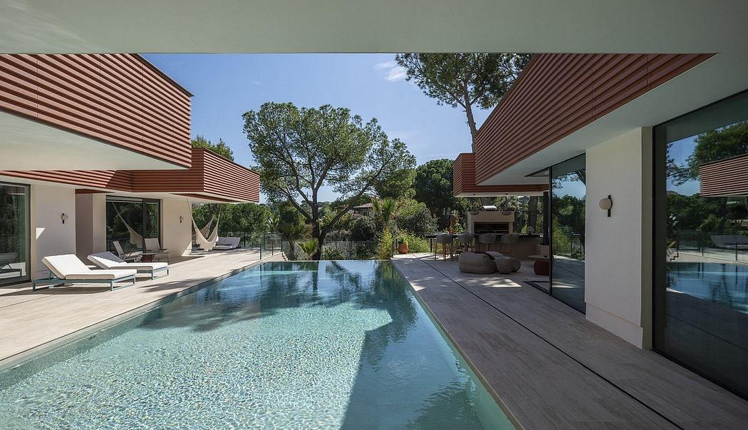 Contemporary villa with sleek red-toned canopy structures, infinity pool, and outdoor lounge.