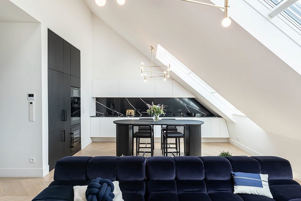 Sleek attic kitchen with skylights, black accents, and navy sofa