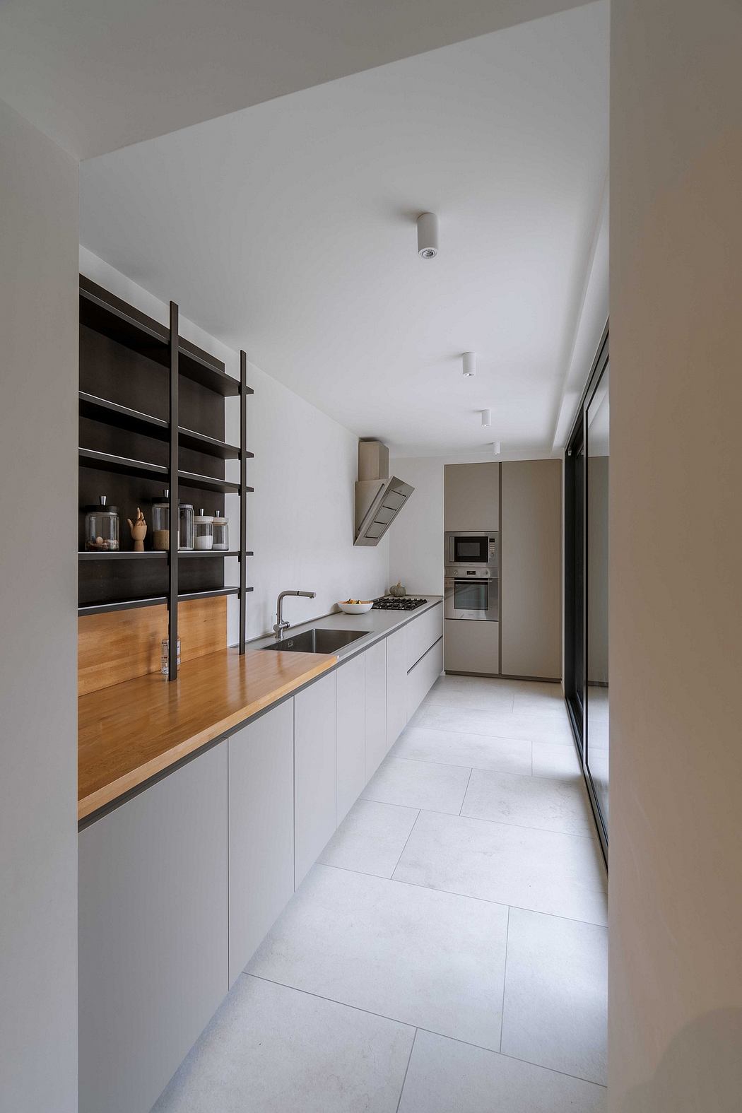 Sleek narrow kitchen with wood countertops and white cabinetry.