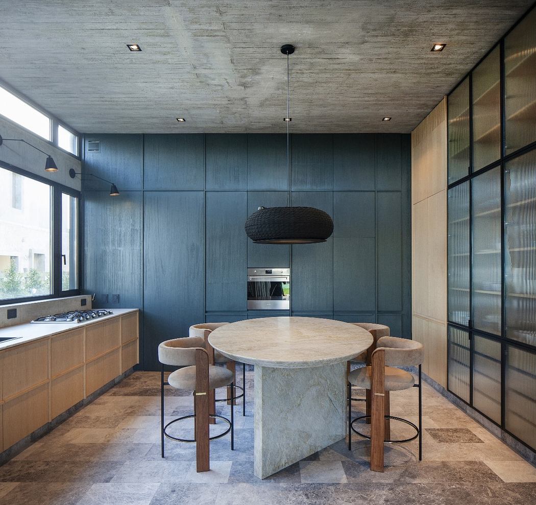 Modern kitchen with a round table, upholstered chairs, and a pendant light.